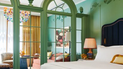 Hotel room with classical green wooden framing separating the lounge area from the bed