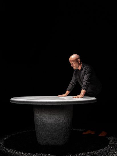 Vincent Van Duysen standing over a stone table