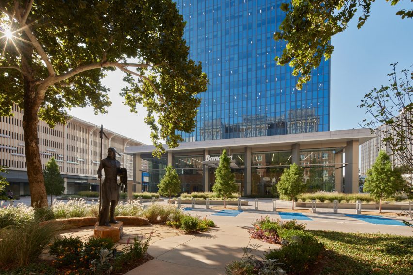 the entrance to a skyscraper surrounded by landscaping