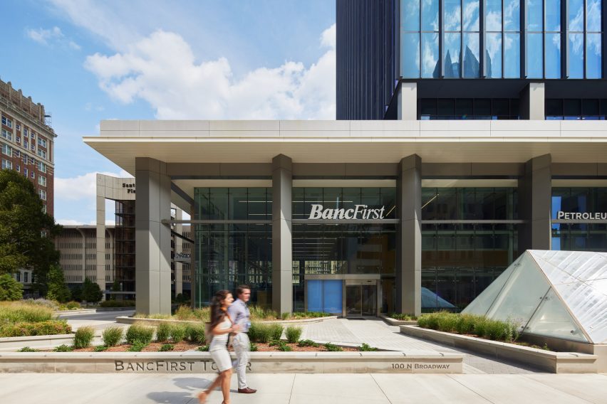 two people walking by the entrance to a skyscraper