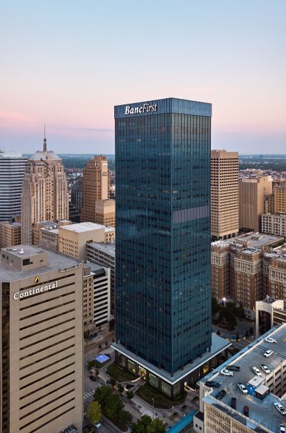 a dark tower in a city surrounded by light buildings
