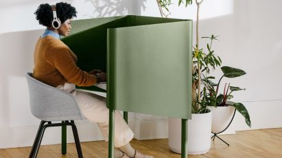 Woman sits at green enclosed desk