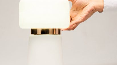 a modern table lamp and a hand holding it on the right side