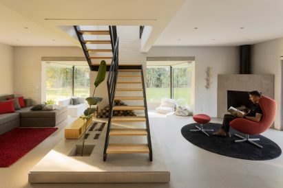 a liviing room with a red chair and exposed staircase