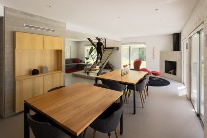 a dining area with wooden tables and a staircase at its centrea