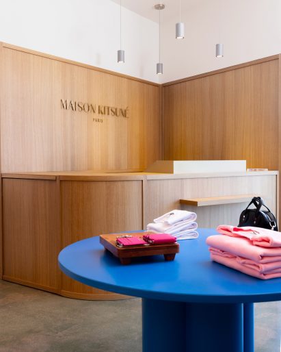 Maison Kitsuné boutique with oak panelling and bright blue central table