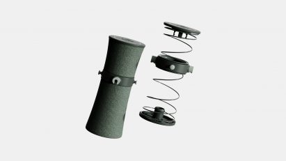 Image of a spring with plastic connectors, and on the left-hand side of it, a textile-covered cylinder in the same size and shape
