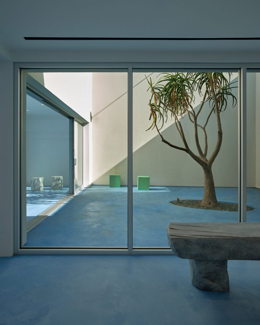 a stone bench and courtyard with tree and two small stools