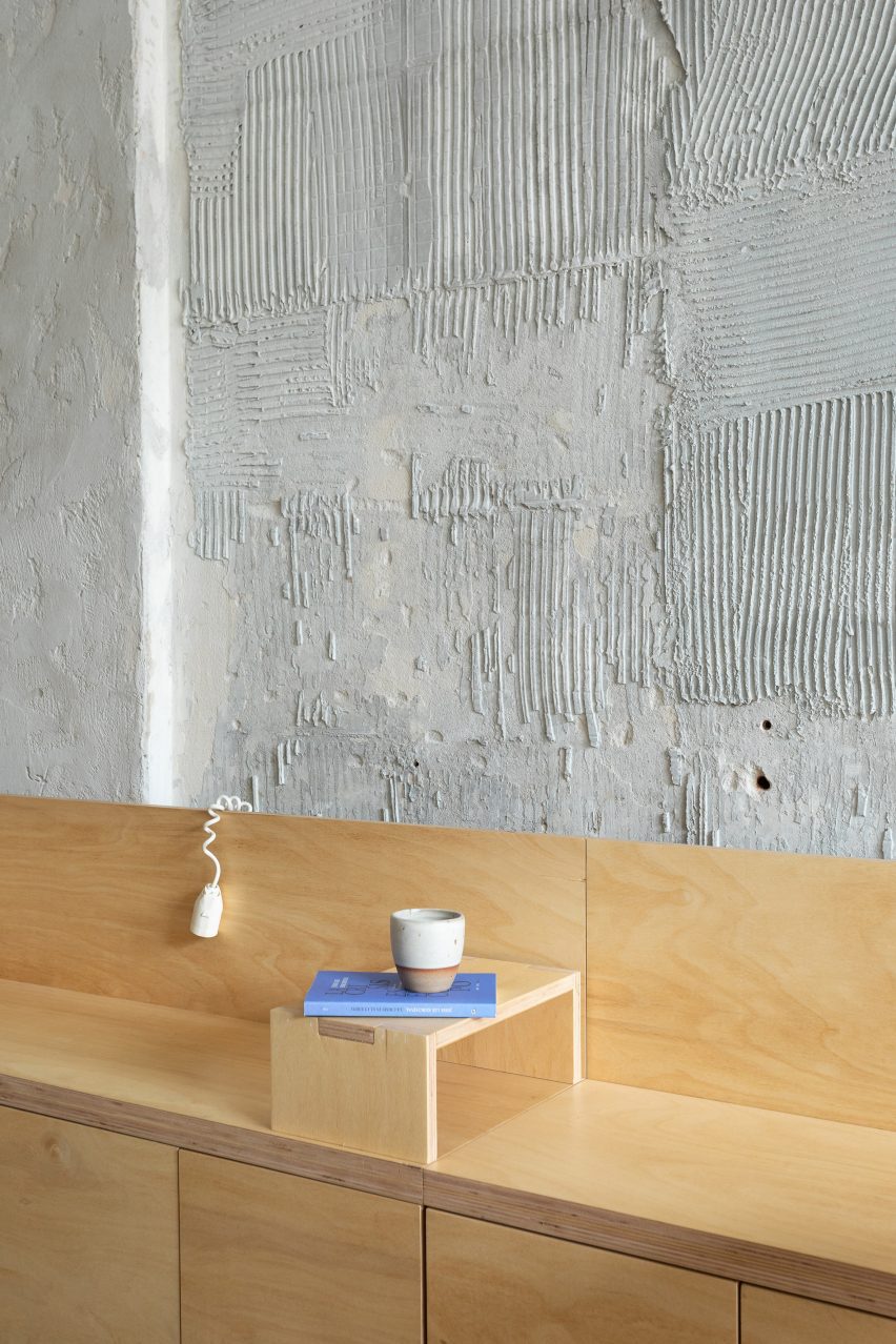 A wooden bench in front of a concrete wall