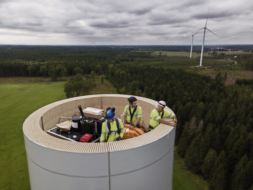 Photo of three people in work gear on top of an incomplete wooden tower