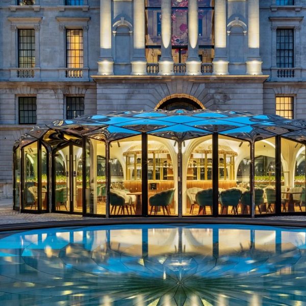 Café pavilion with silver roof reflected onto pond
