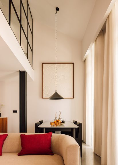 Double-height living and dining room with a long pendant lamp suspended over the table