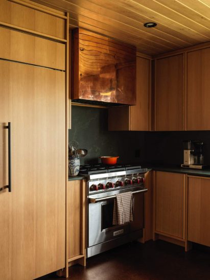 Honey-toned wood kitchen with soapstone surfaces and a copper range hood