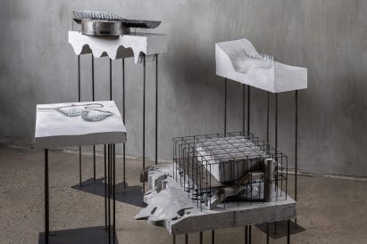Four architectural models on plinths made from concrete and metal