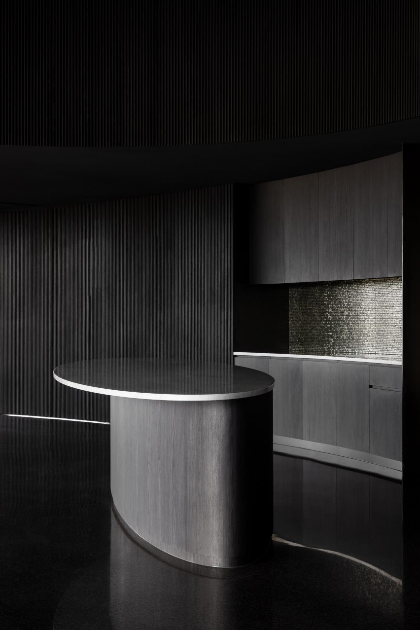 Kitchen with a black rounded island and black timber walls