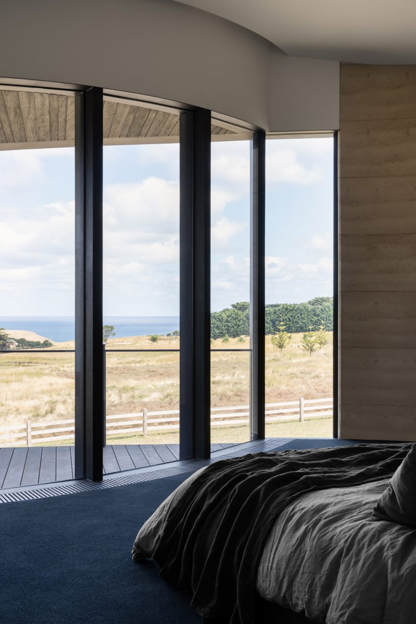 Bedroom with floor-to-ceiling windows overlooking a grassy landscape