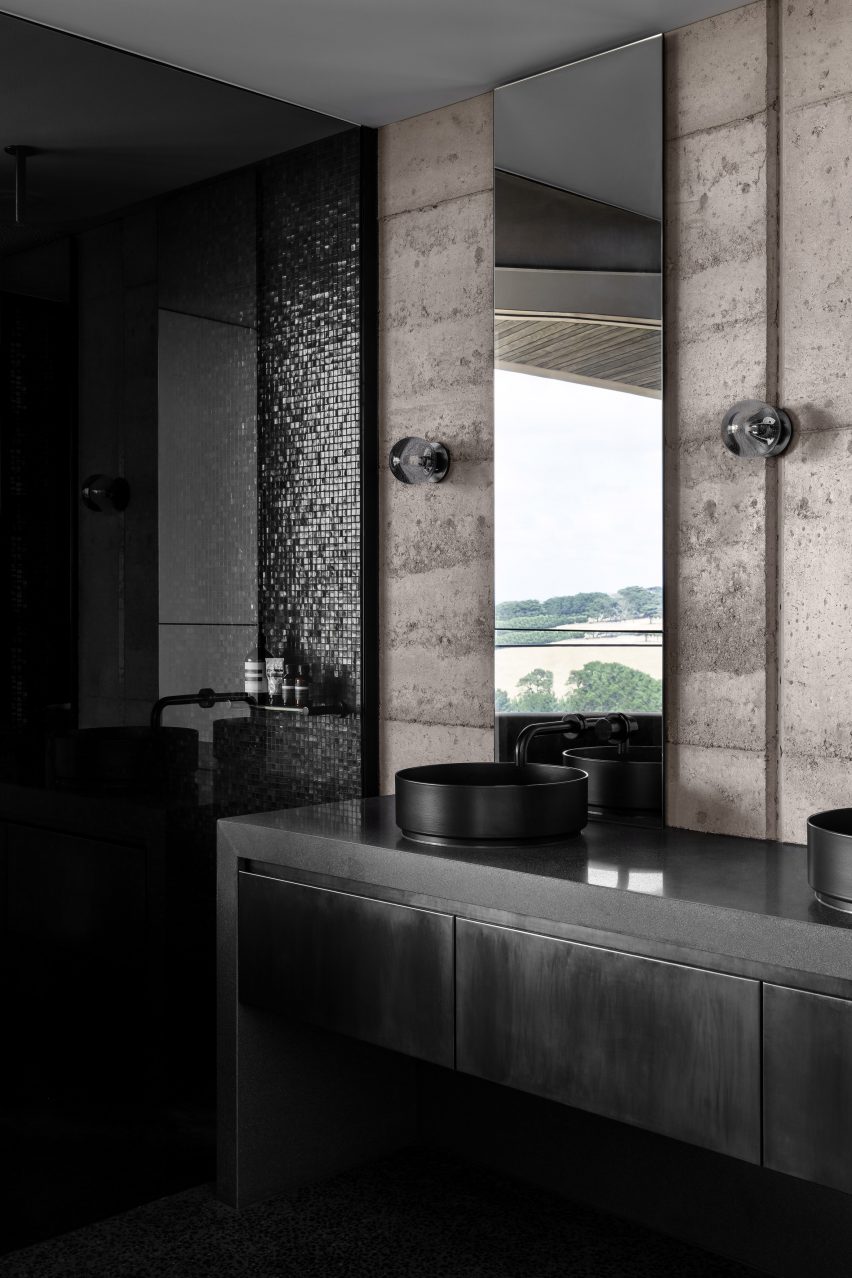Bathroom with rammed earth walls and black sinks