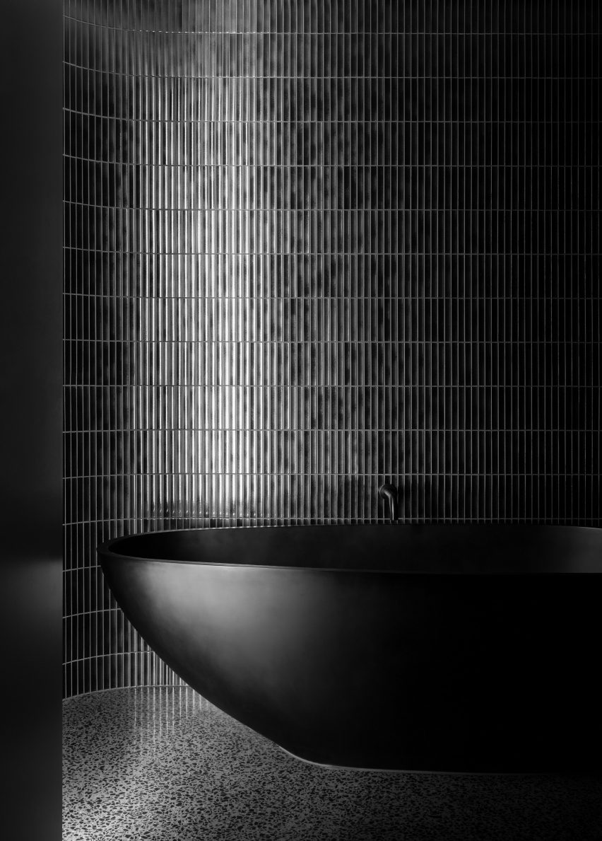Black tiled bathroom with a black bathtub
