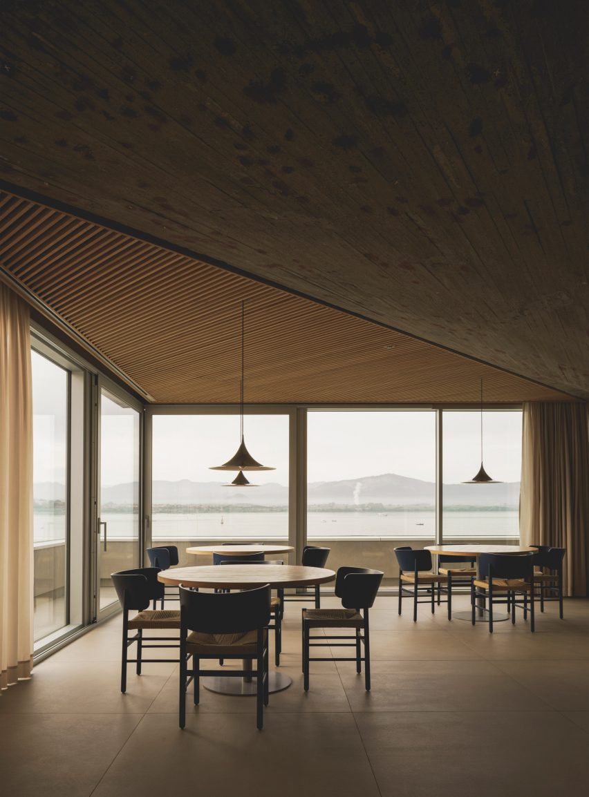 Dining tables overlooking views of the bay inside a brutalist restaurant in Spain by Zooco Estudio
