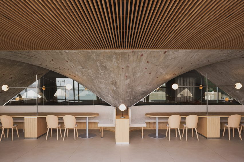 Concrete paraboloid and dining tables inside brutalist restaurant in Spain by Zooco Estudio