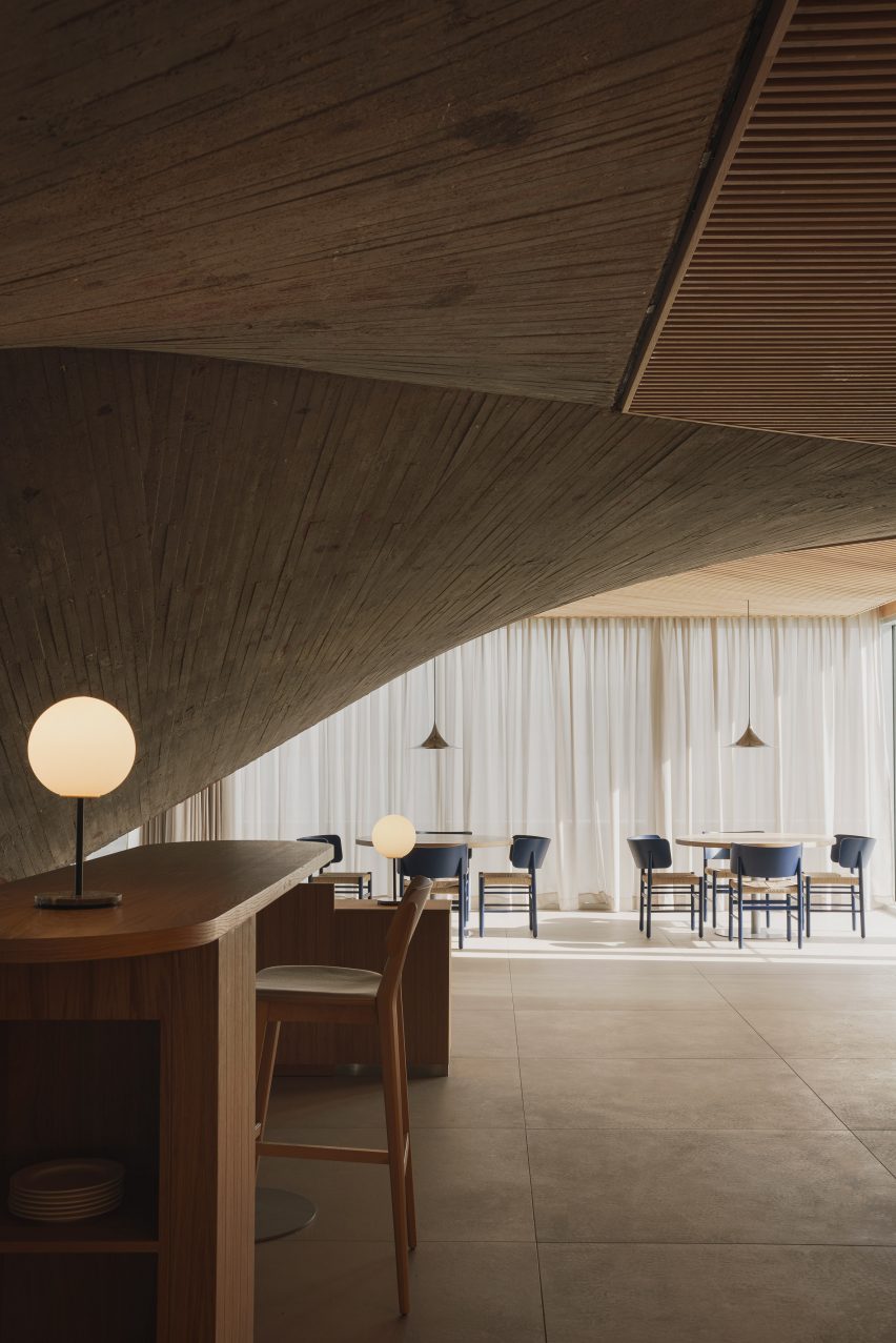 Dining tables alongside a curtained wall inside a brutalist restaurant in Spain by Zooco Estudio
