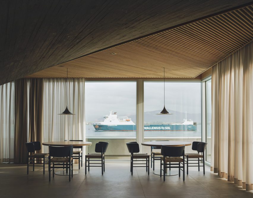 Dining tables overlooking views of the bay inside a brutalist restaurant in Spain by Zooco Estudio