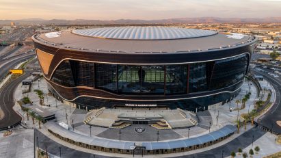 Allegiant Stadium, which will host the Super Bowl, with the field and torch visible through the black glass