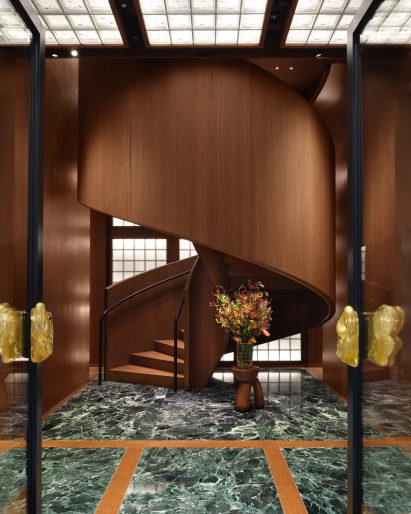 Walnut spiral staircase rising from green marble floor