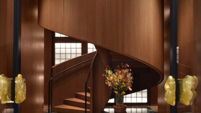Walnut spiral staircase rising from green marble floor in Bottega Veneta's Milan store