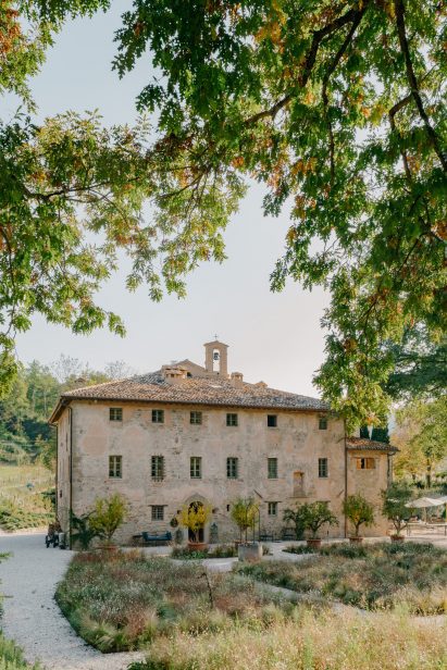 Exterior of converted monastery building with a bell tower, surrounded by landscaping