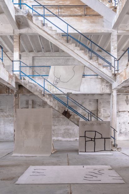 Four rugs displayed in a high-ceilinged space