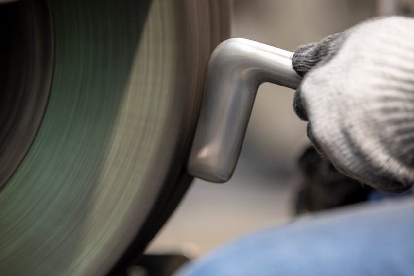Close-up photo of a worker polishing a silver-coloured metal door handle