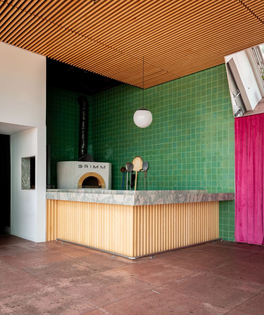 A green tile wall surrounding pizza oven