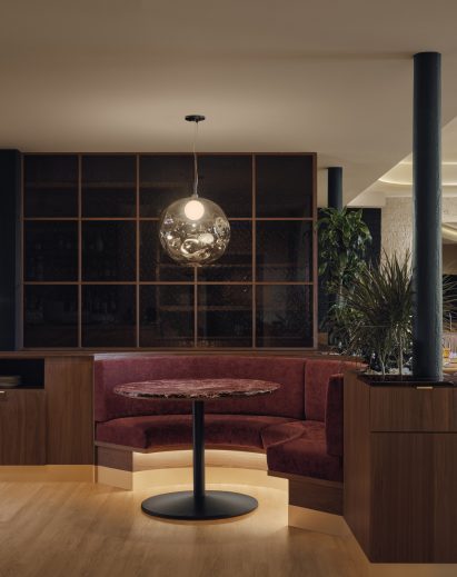 A red-hued semicircular booth tucked into walnut millwork