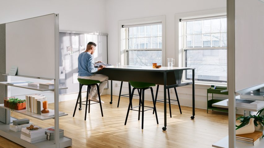 A man works at a co-working desk as light streams through the window