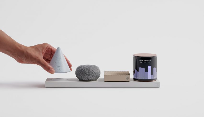 Photo of a hand grabbing a small, inverted cone-shaped light grey object from a rectangular base plate containing three other small objects