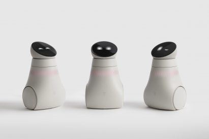 Photo of three small robots on wheels with round head units holding a display screen showing two dots like eyes in either a closed, open or winking position
