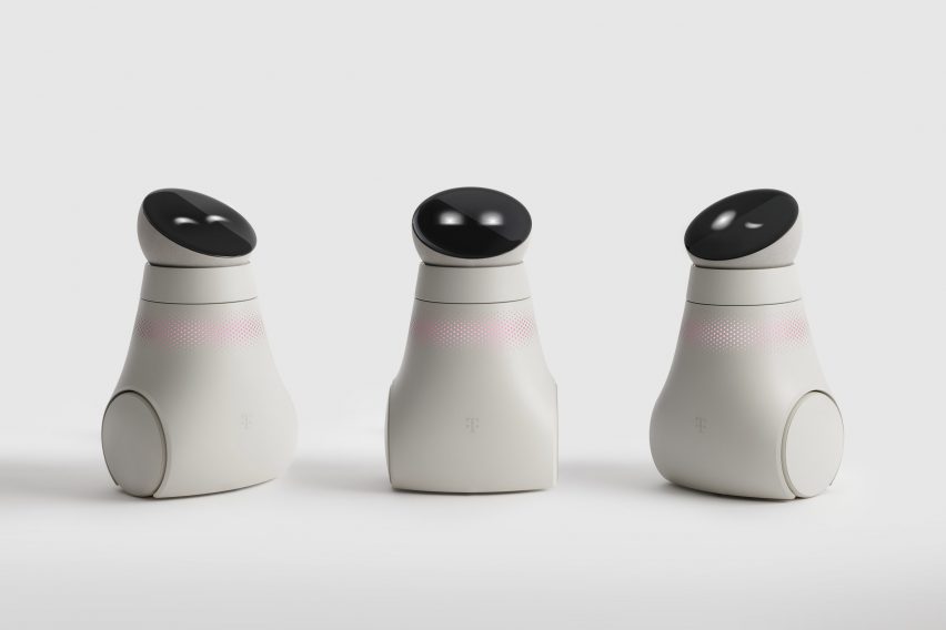 Photo of three small robots on wheels with round head units holding a display screen showing two dots like eyes in either a closed, open or winking position