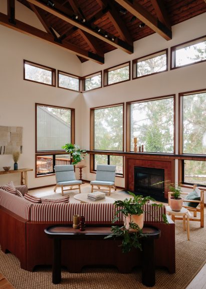 Double-height lounge space with large windows and a red striped sofa