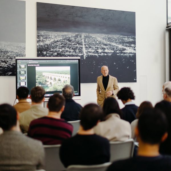 class of students looking at the teacher presenting on a scree