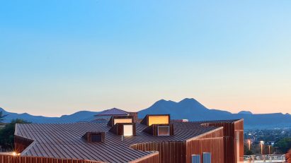 Corten steel museum at dusk with mountains in the background