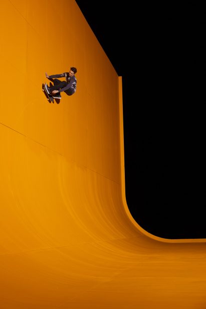Man on vertical wall with skateboard