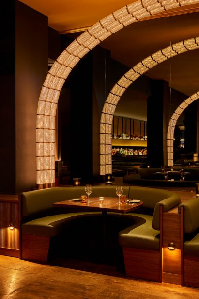 Glass and bronze modules form an arch of light over a dining booth