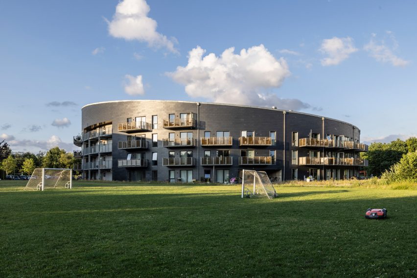 Circular slate-clad building surrounded by a green field
