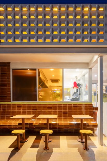Straight-stack tilework covers a built-in bench in the outdoor dining area