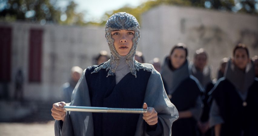 Dune Part Two production photo showing Princess Irulan looking shocked while holding a scroll in a leafy outdoor setting