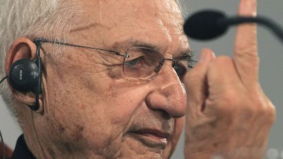 Frank Gehry holding up his middle finger at a press conference in 2014