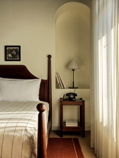 Bedroom with dark wood furniture and lighter-toned walls and textiles