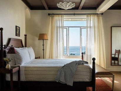 Guest room with cream walls, linen curtains and shell pendant light