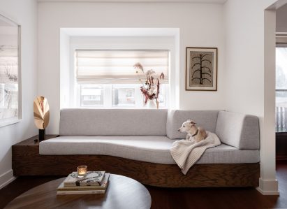 A built-in sofa under a living room bay window